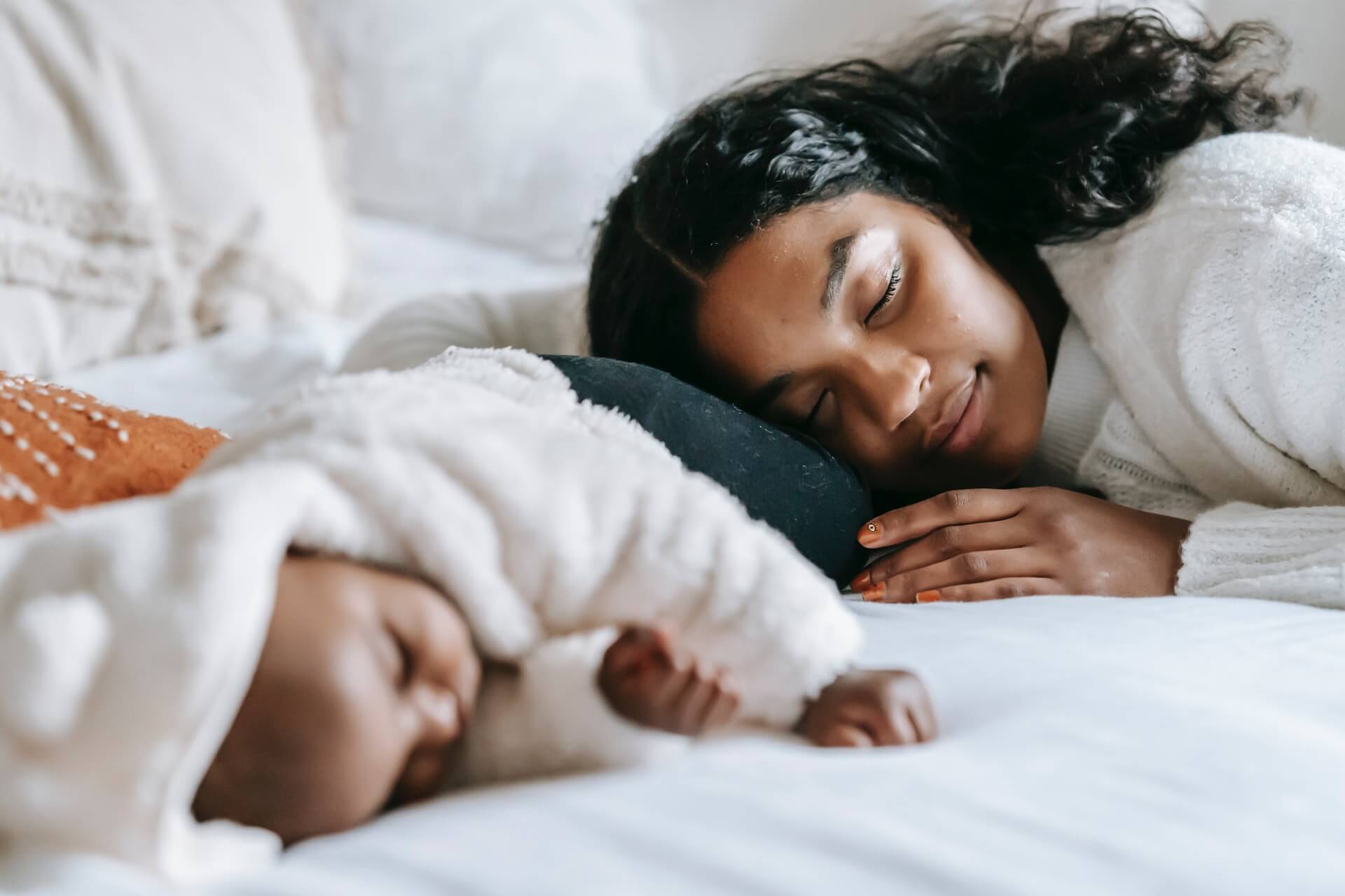 woman sleeping next to baby with bedrock balm night cream