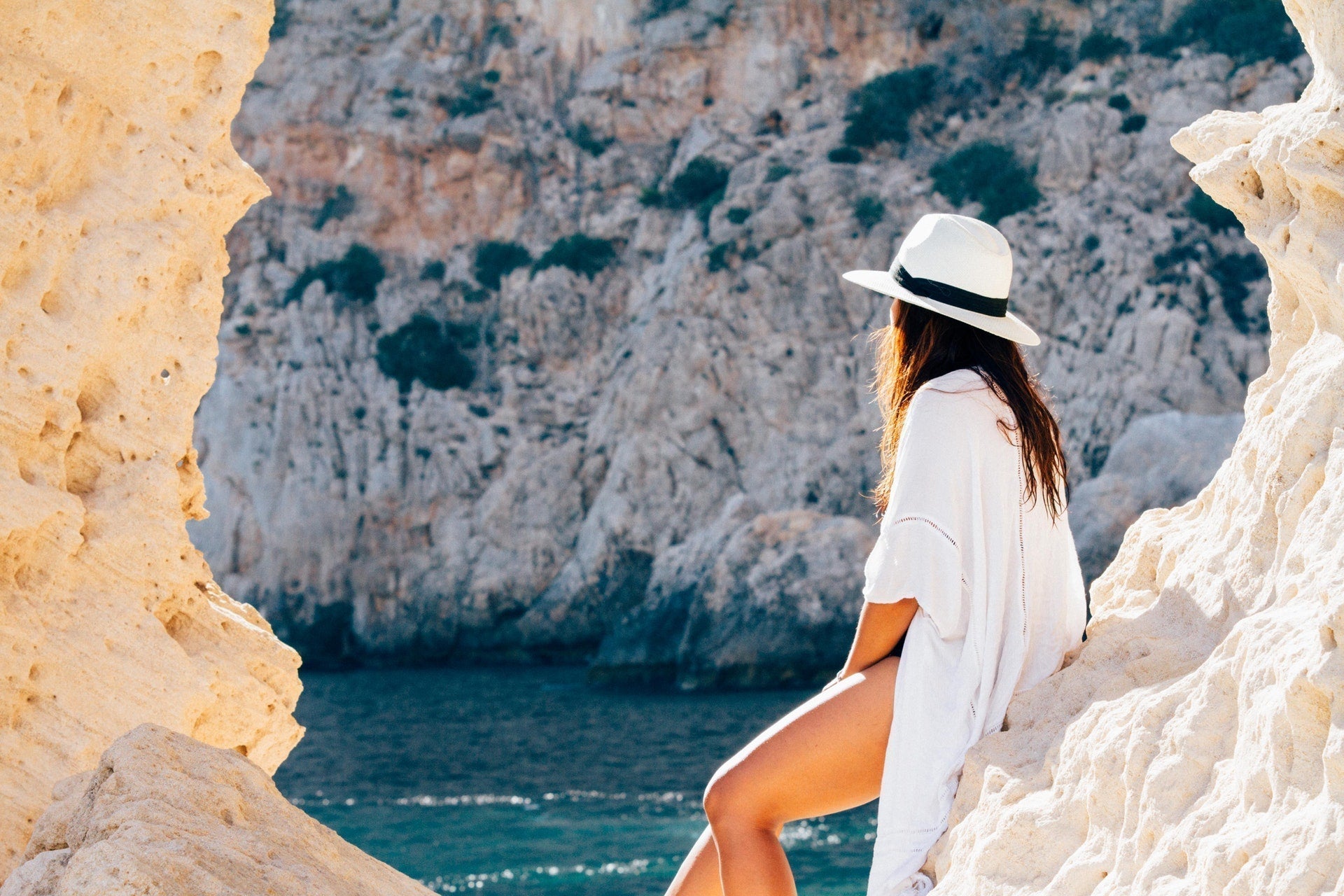 woman sitting by rocks and water