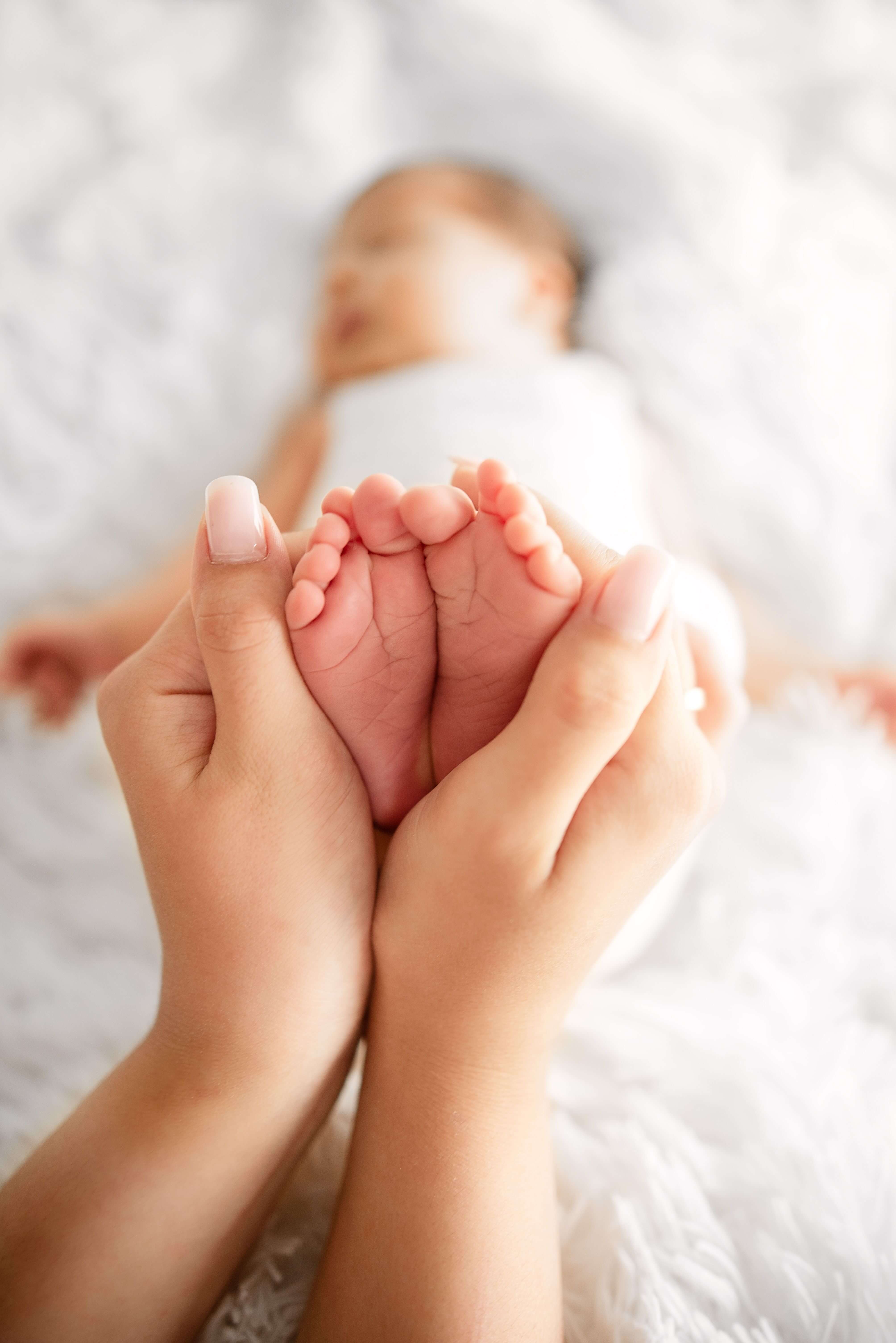 new born baby feet held by parent