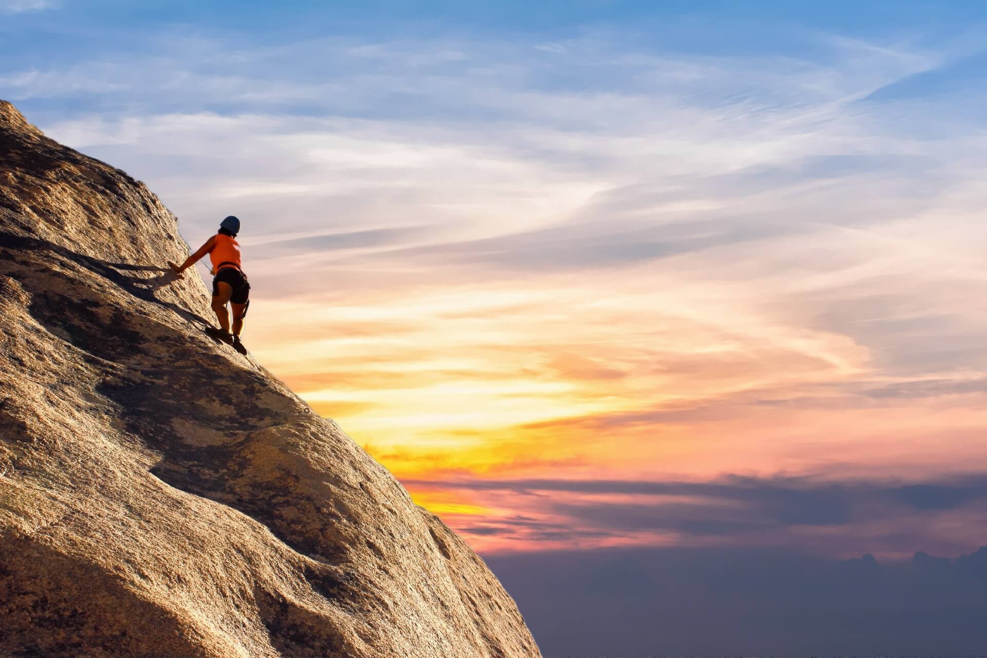 woman hiking cliff during sunset
