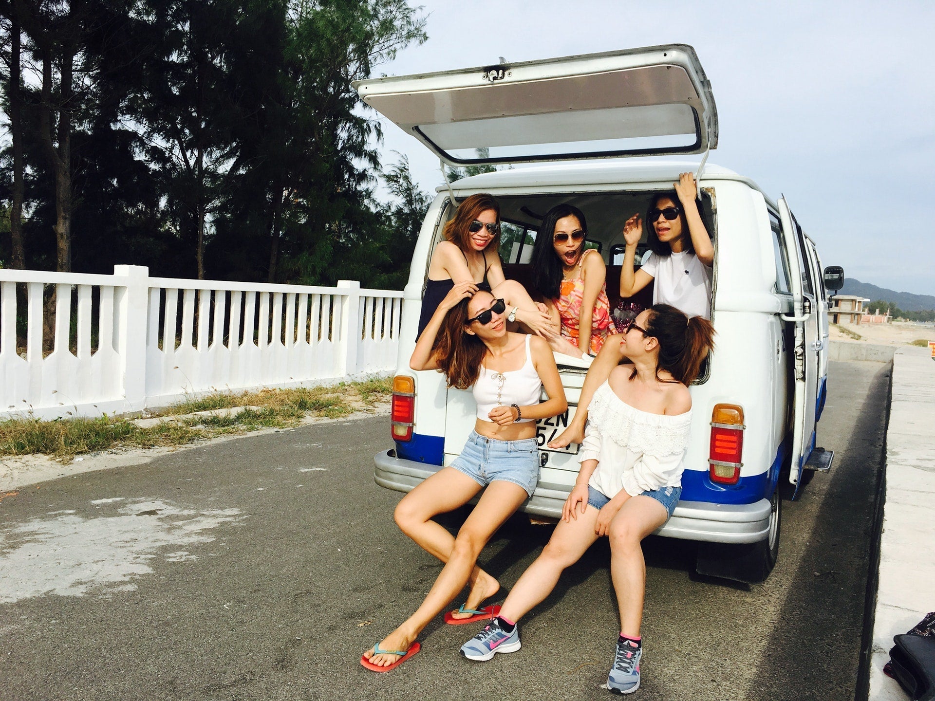a group of women by the beach hanging out in a van