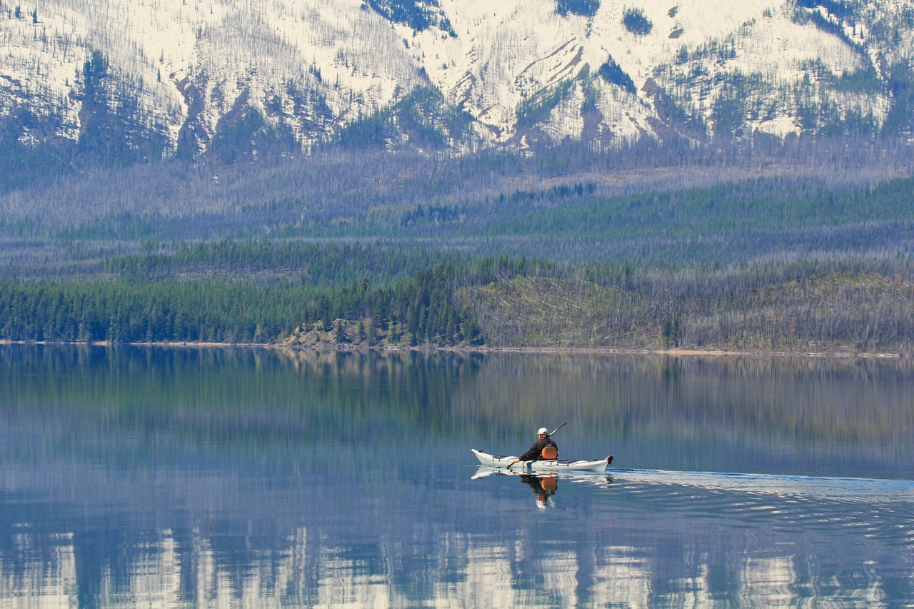 person kayaking by the mountains on a lake