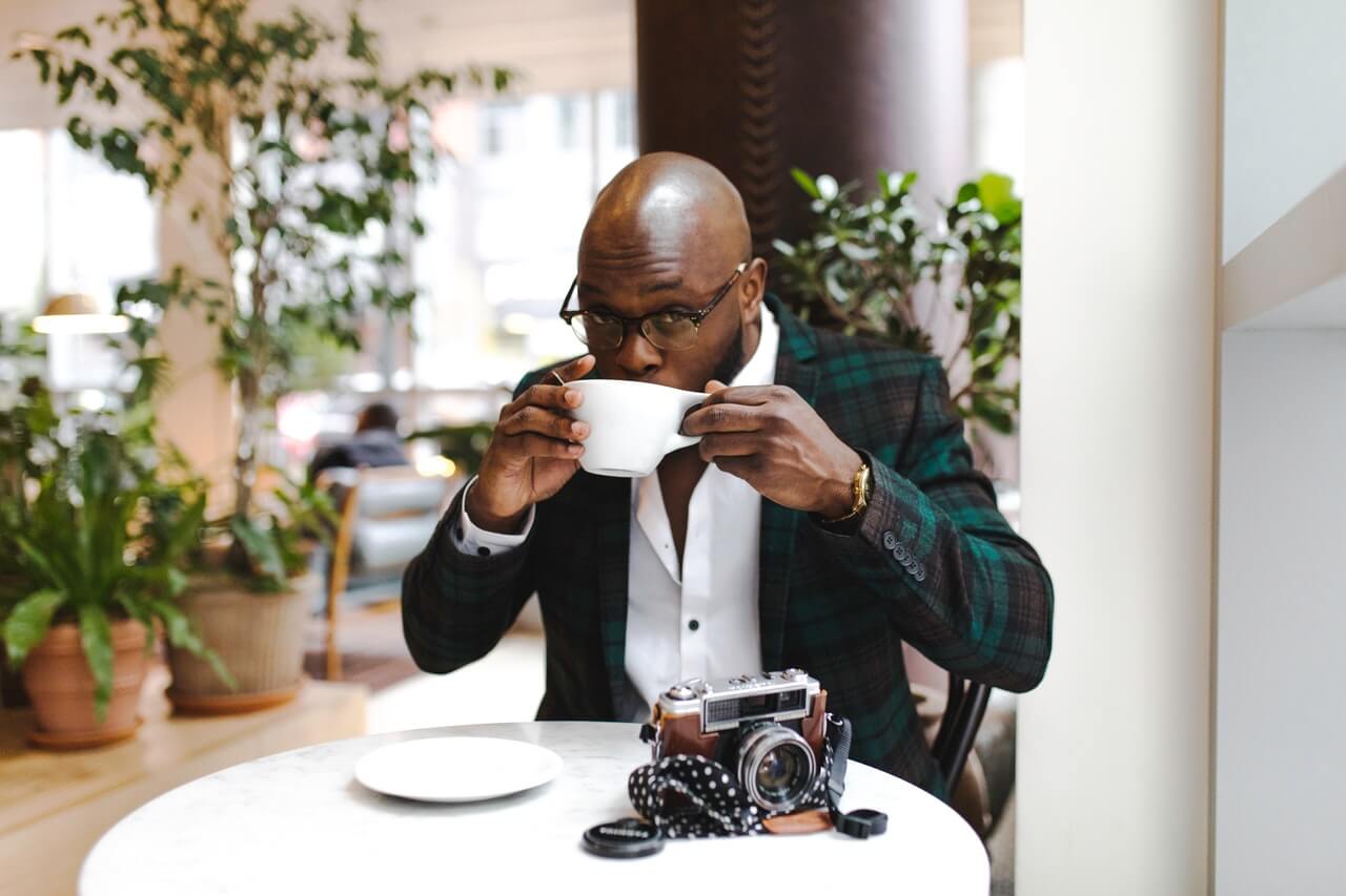 man drinking coffee in a restaurant with shaved head